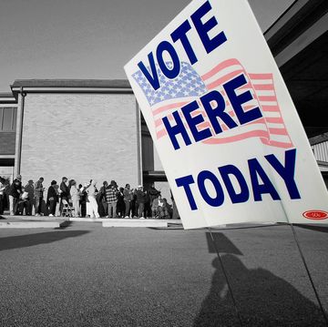 a black and white photo of people lined up to vote with a sign that says vote here today in color